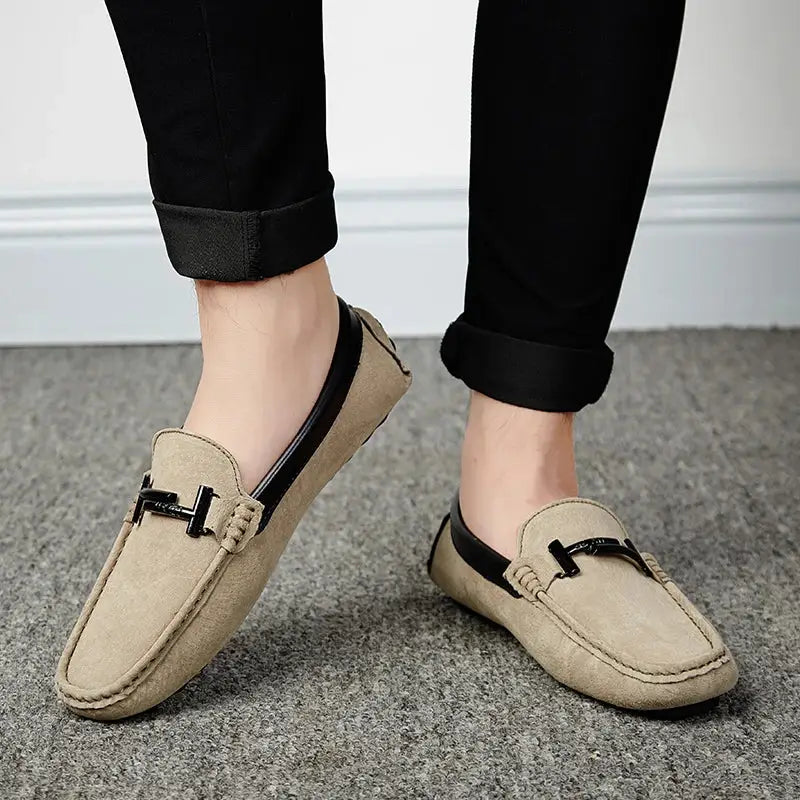 Bej suede loafers with black metal buckle details paired with rolled-up black pants for everyday style