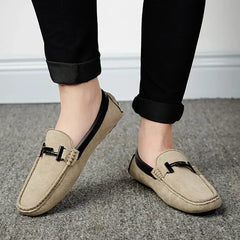 Bej suede loafers with black metal buckle details paired with rolled-up black pants for everyday style